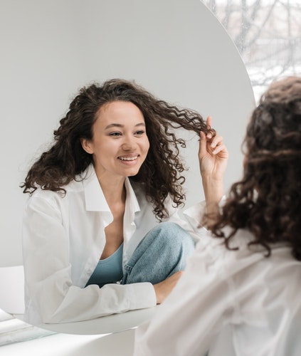 mujer de cara redonda mirándose feliz al espejo